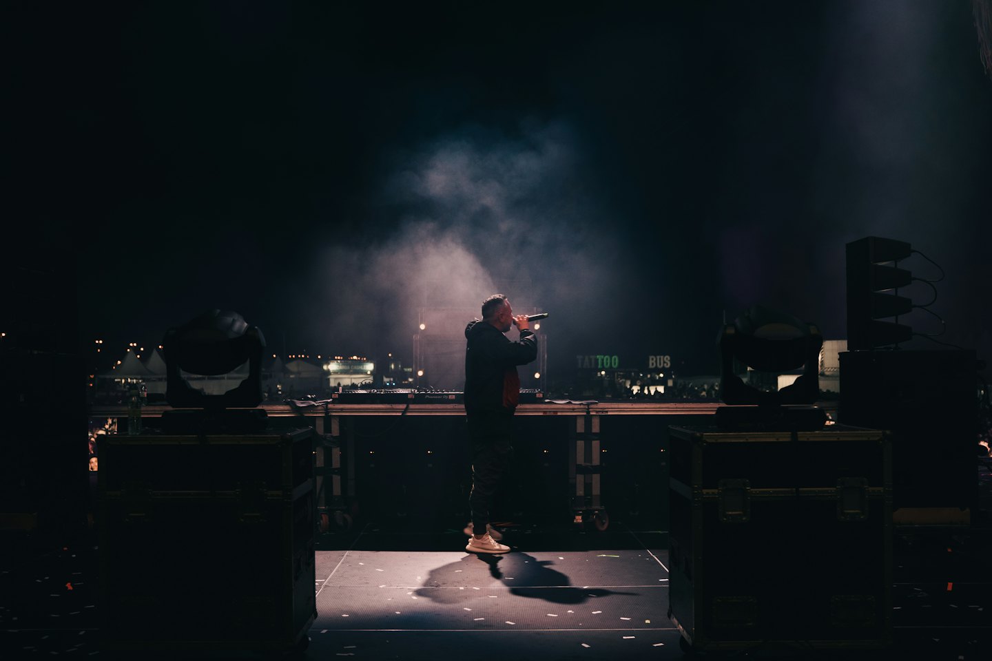 Rapper performs on an outdoor stage at night with a microphone.