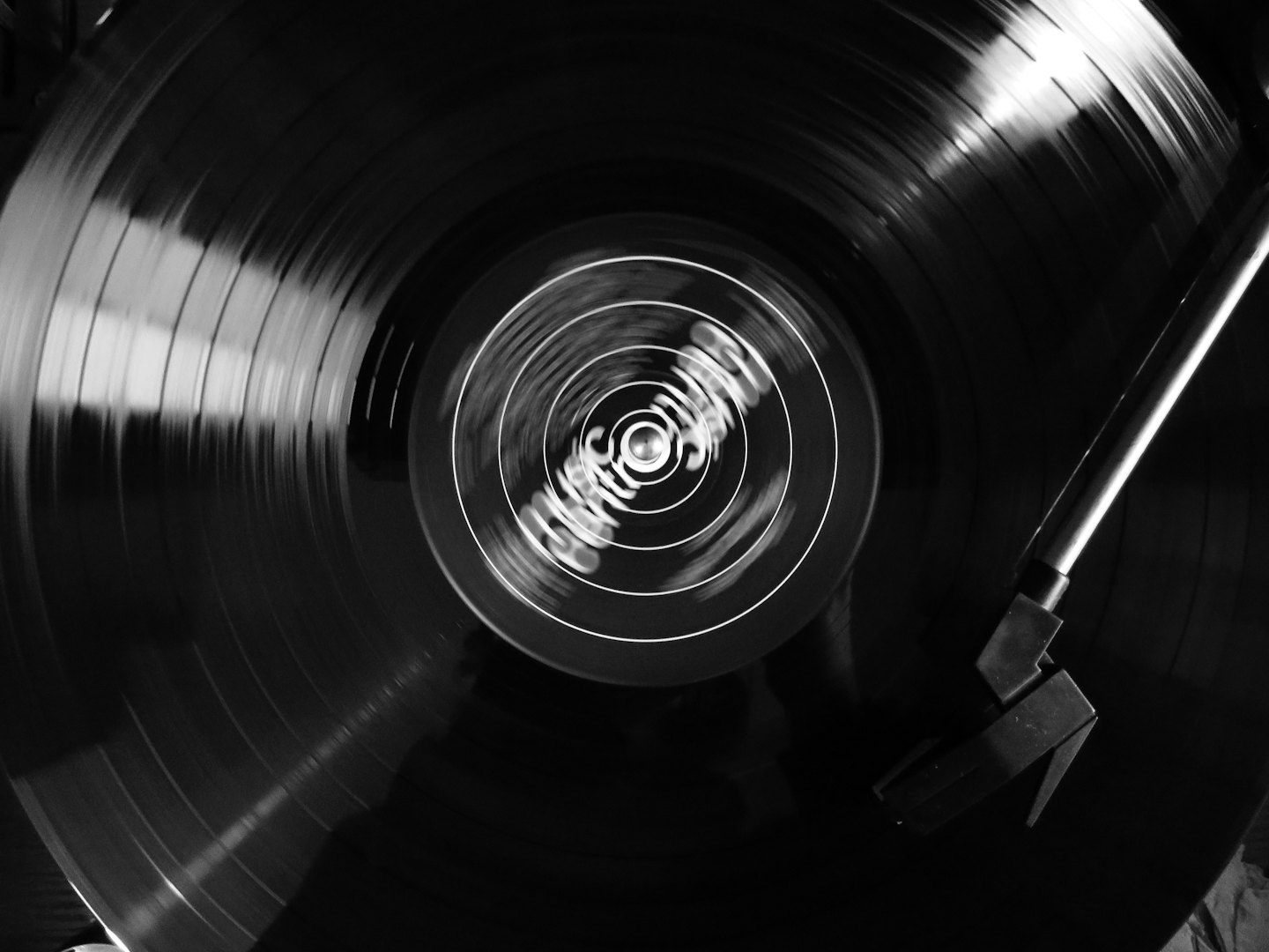A vinyl record spins on a turntable with the tonearm engaged.