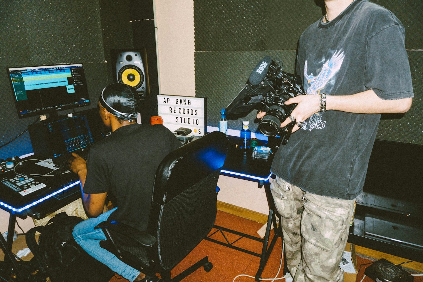 Audio engineer and videographer working together in a recording studio.