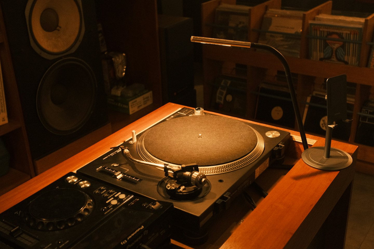 Turntable and DJ mixer sitting on a wooden console.