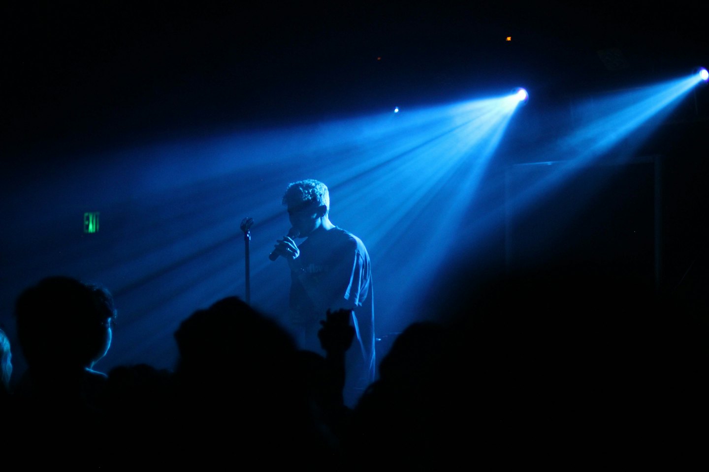 Performer holding microphone under blue stage lights.