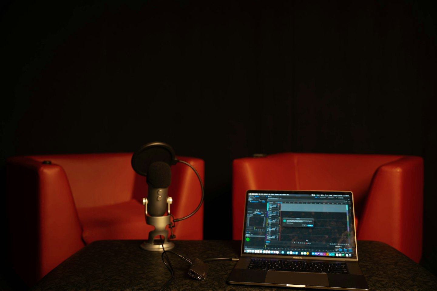 Microphone and laptop on a table for podcast recording.